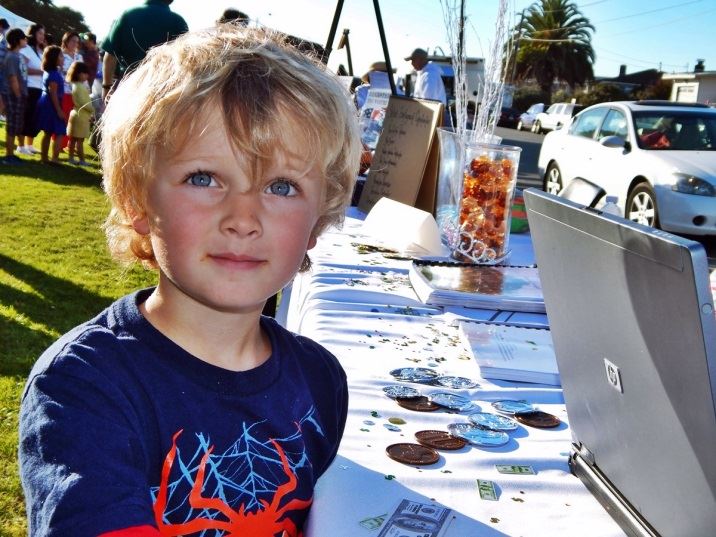 Little Boy standing near table outside of City Hall lawn